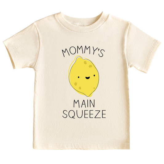 A kid's t-shirt with a cute printed graphic of a lemon and the text 'Mama's Main Squeeze.' This adorable t-shirt celebrates the special bond between a child and their mama. 