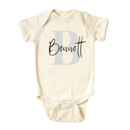 Natural Baby Onesie with grey initial design and customizable name.