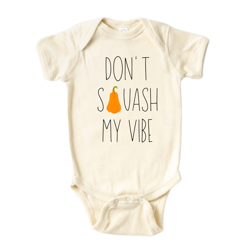 Natural onesie featuring a fall-themed printed graphic of a squash and the fun text 'Don't Squash My Vibe.' Explore this trendy tee, perfect for embracing autumn style. 