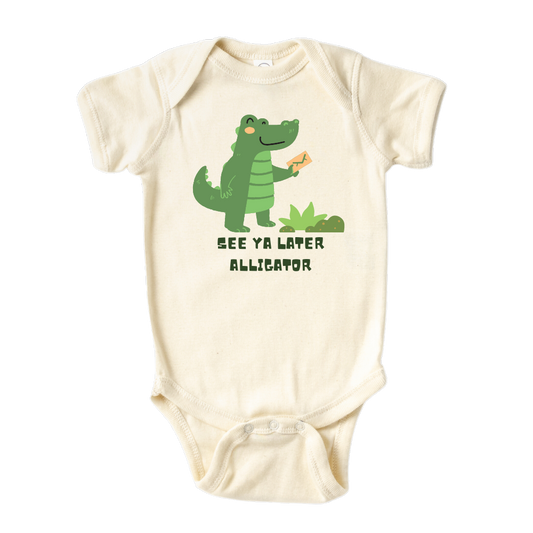 Natural Baby Onesie showcasing a playful printed graphic of an alligator and the text 'See Ya Later Alligator.' Explore this delightful tee that adds a touch of whimsy and charm to your child's wardrobe.