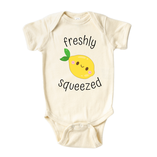 A kids' t-shirt with an adorable graphic of a cute lemon and the text 'Freshly Squeezed.' This design captures the refreshing and playful nature of the citrus fruit, adding a vibrant touch to the wearer's style. It's a delightful and eye-catching tee that stands out with its zestful charm.