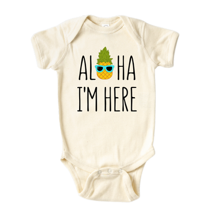 A kids' t-shirt with a pineapple wearing glasses and the text 'Aloha I'm Here.' This fun and tropical design captures the playful spirit, adding a vibrant touch to the wearer's style.